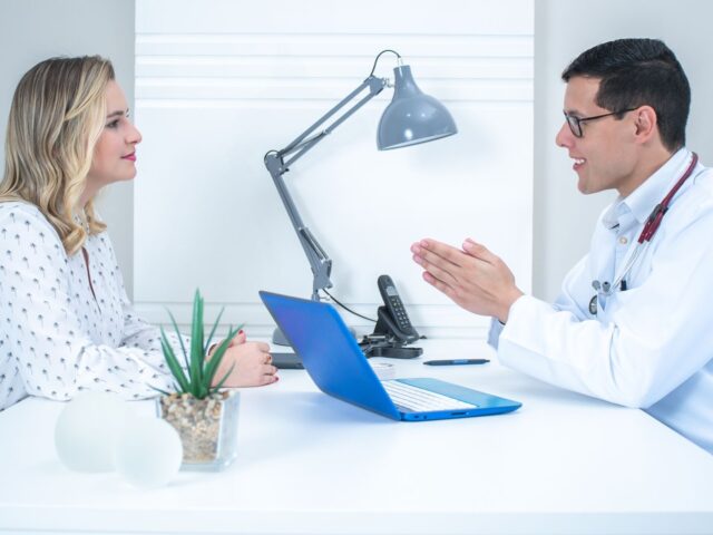 Provider talking with a patient across a desk in a bright office