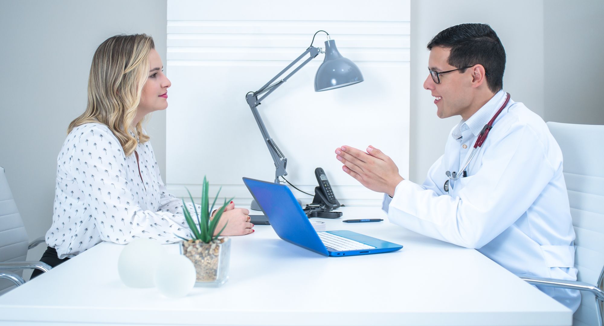 Provider talking with a patient across a desk in a bright office