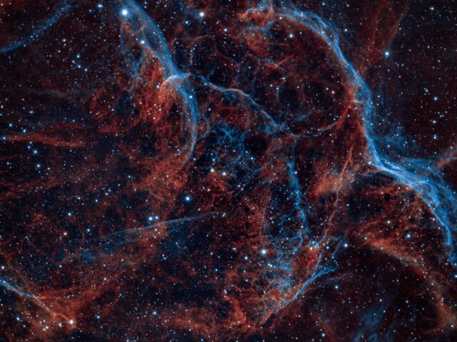 Vela supernova remnant with blue and red filaments against a starfield