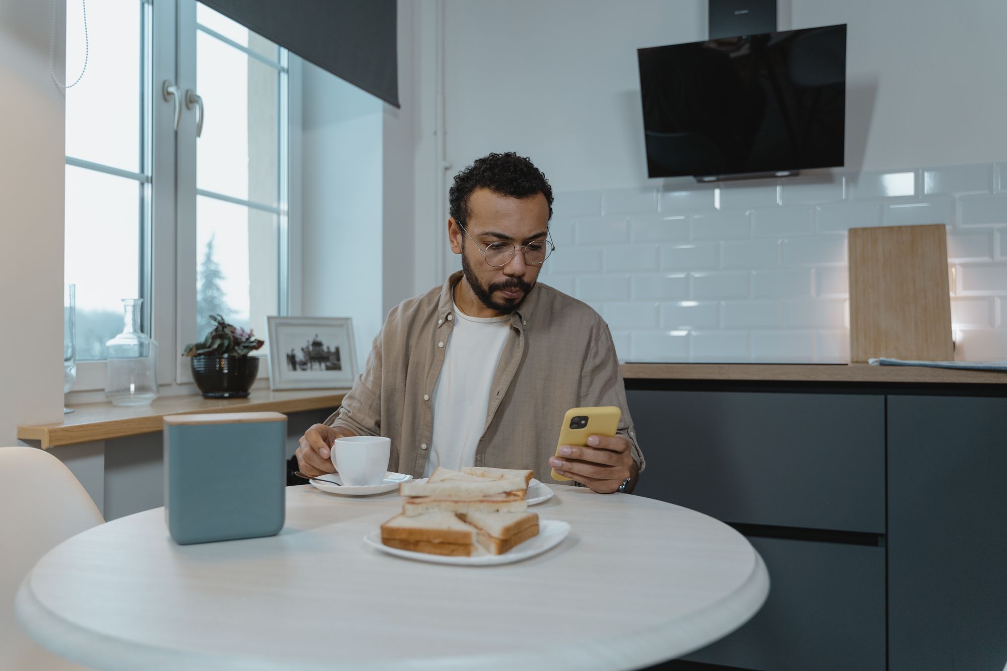 Man completing a form on his phone at his kitchen table