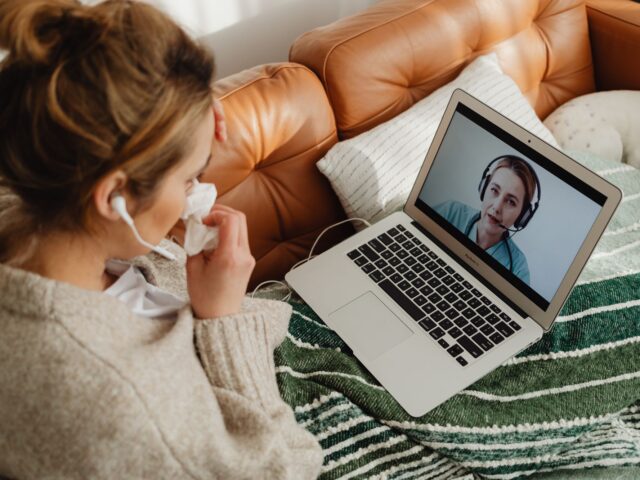 Woman on her sofa having an online consultation on a laptop