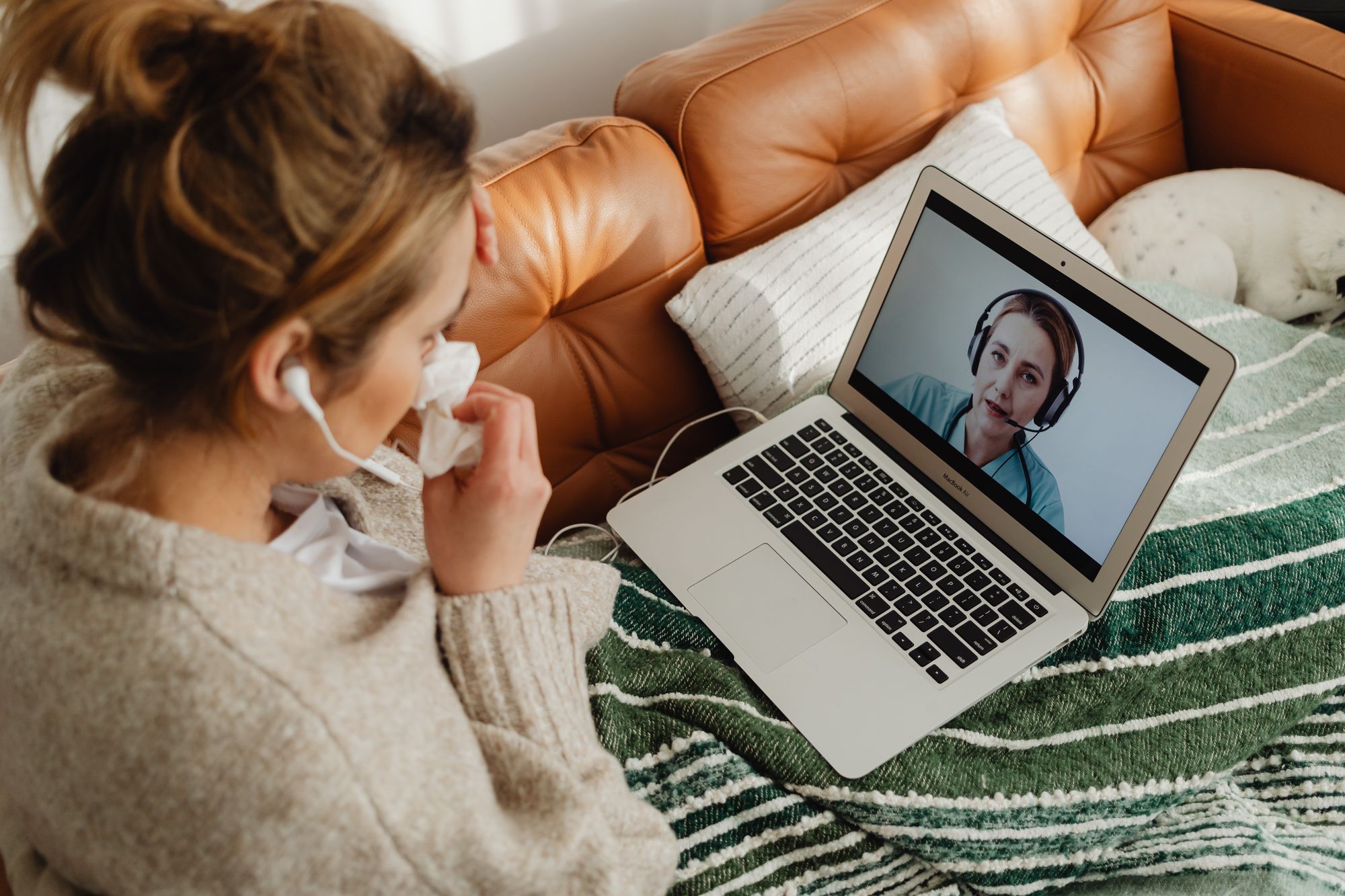 Woman on her sofa having an online consultation on a laptop