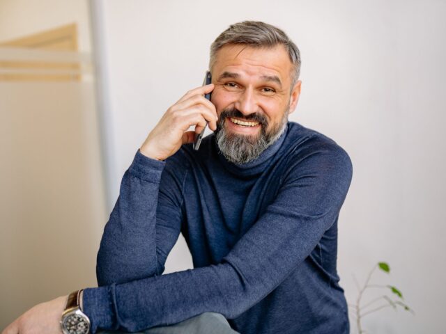 Man smiling while speaking with patient support on the phone