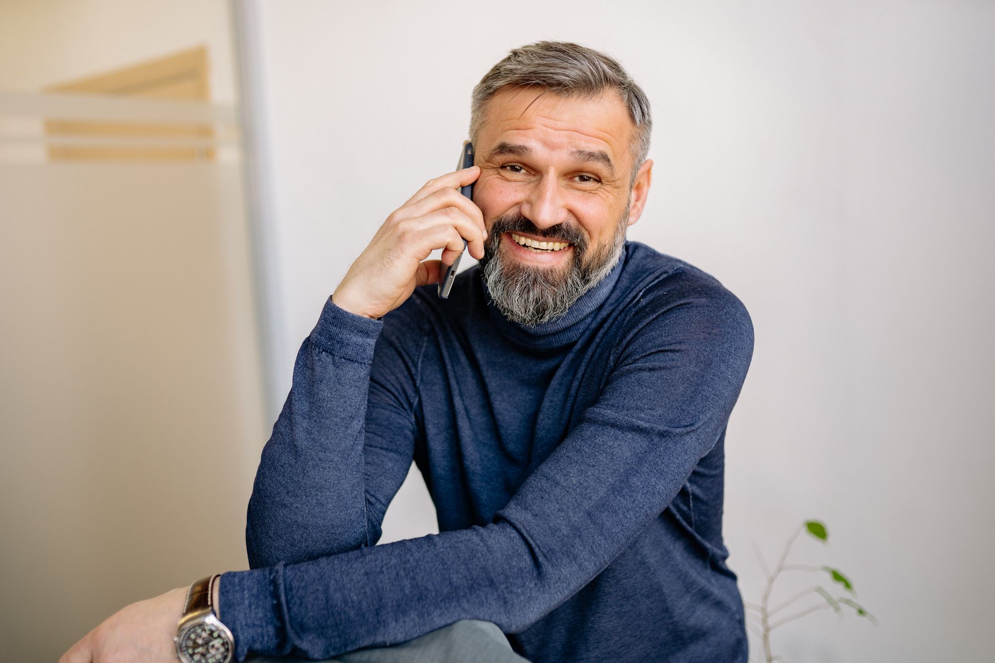 Man smiling while speaking with patient support on the phone
