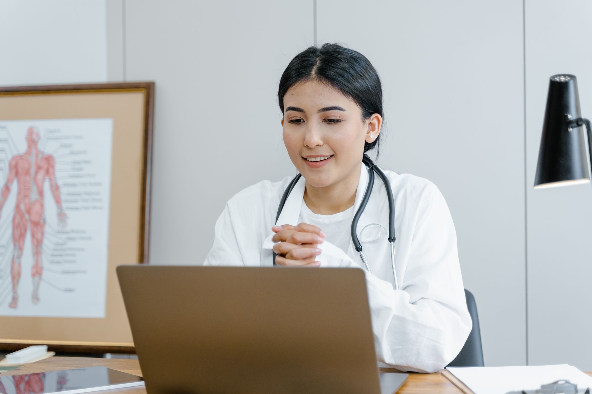 Licensed provider smiling during a telehealth visit at her desk