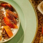 Bowl of yogurt with fruit, seeds and nuts on a breakfast table
