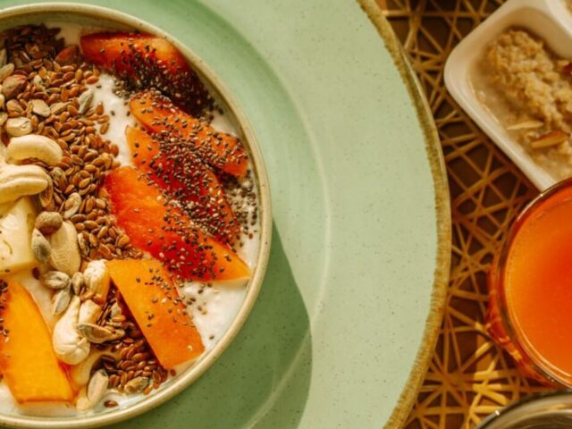 Bowl of yogurt with fruit, seeds and nuts on a breakfast table